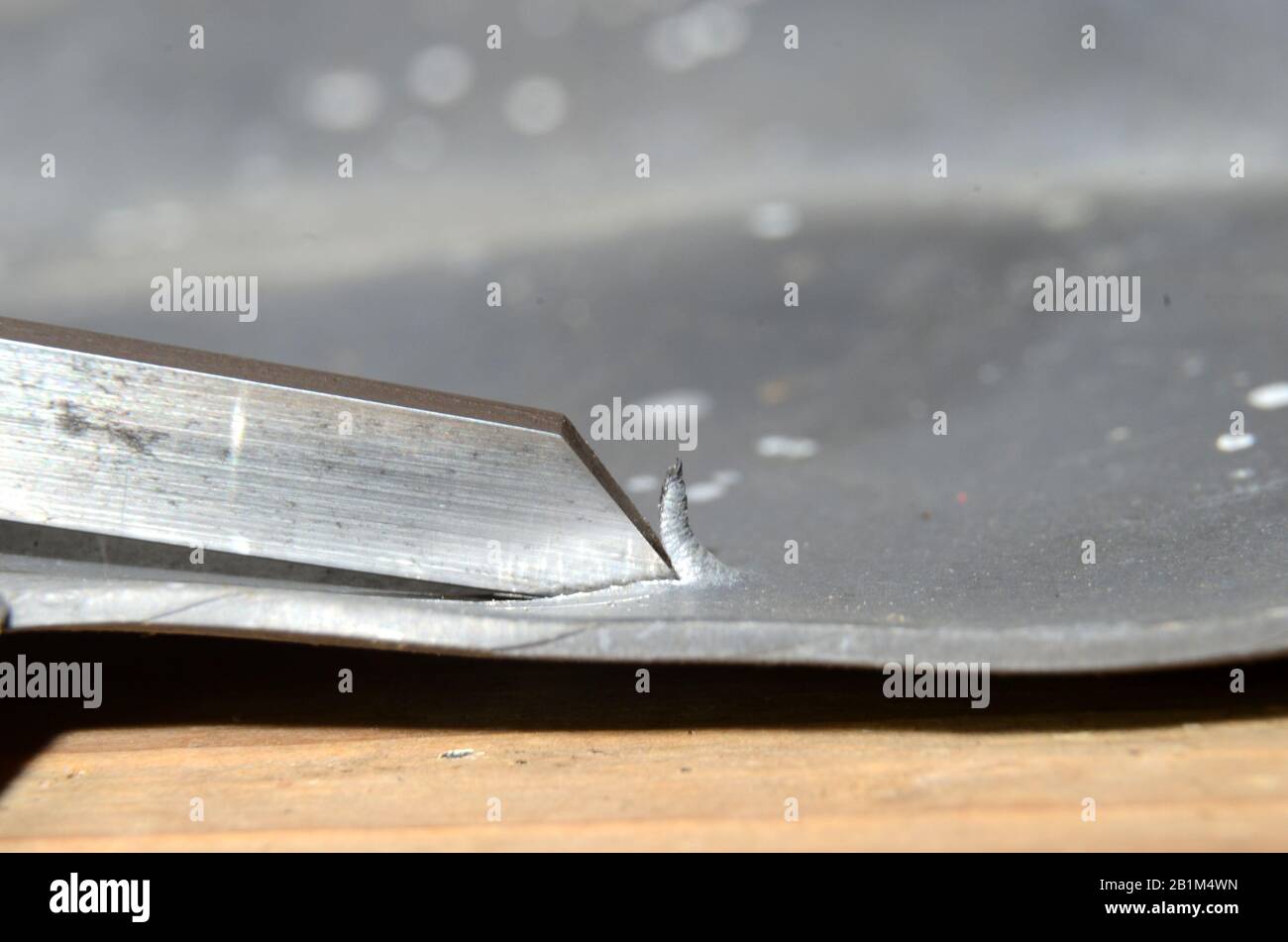 Das auf einem Blech verwendete Werkzeug zum Greben kann man sehen, wie es einen Metallspan angehoben hat. Stockfoto
