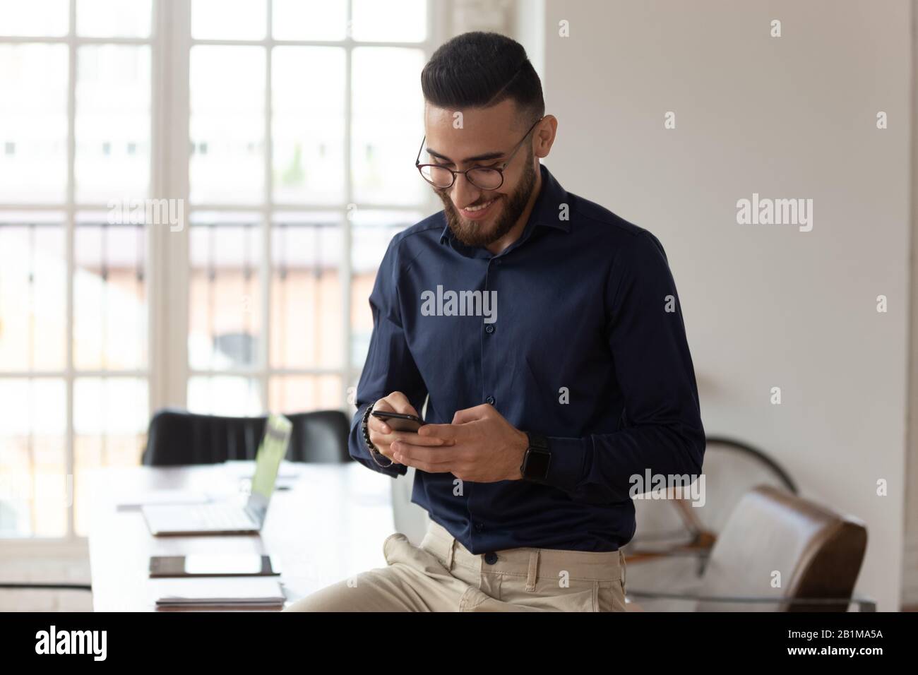 Ein tausendjähriger Unternehmer aus dem mittleren Osten, der Smartphone-Apps im Büro verwendet Stockfoto