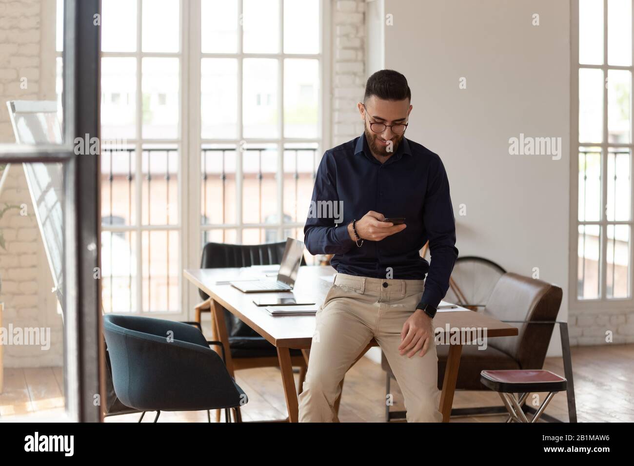 Geschäftsmann aus dem mittleren Osten mit Smartphone im modernen Bürozimmer Stockfoto