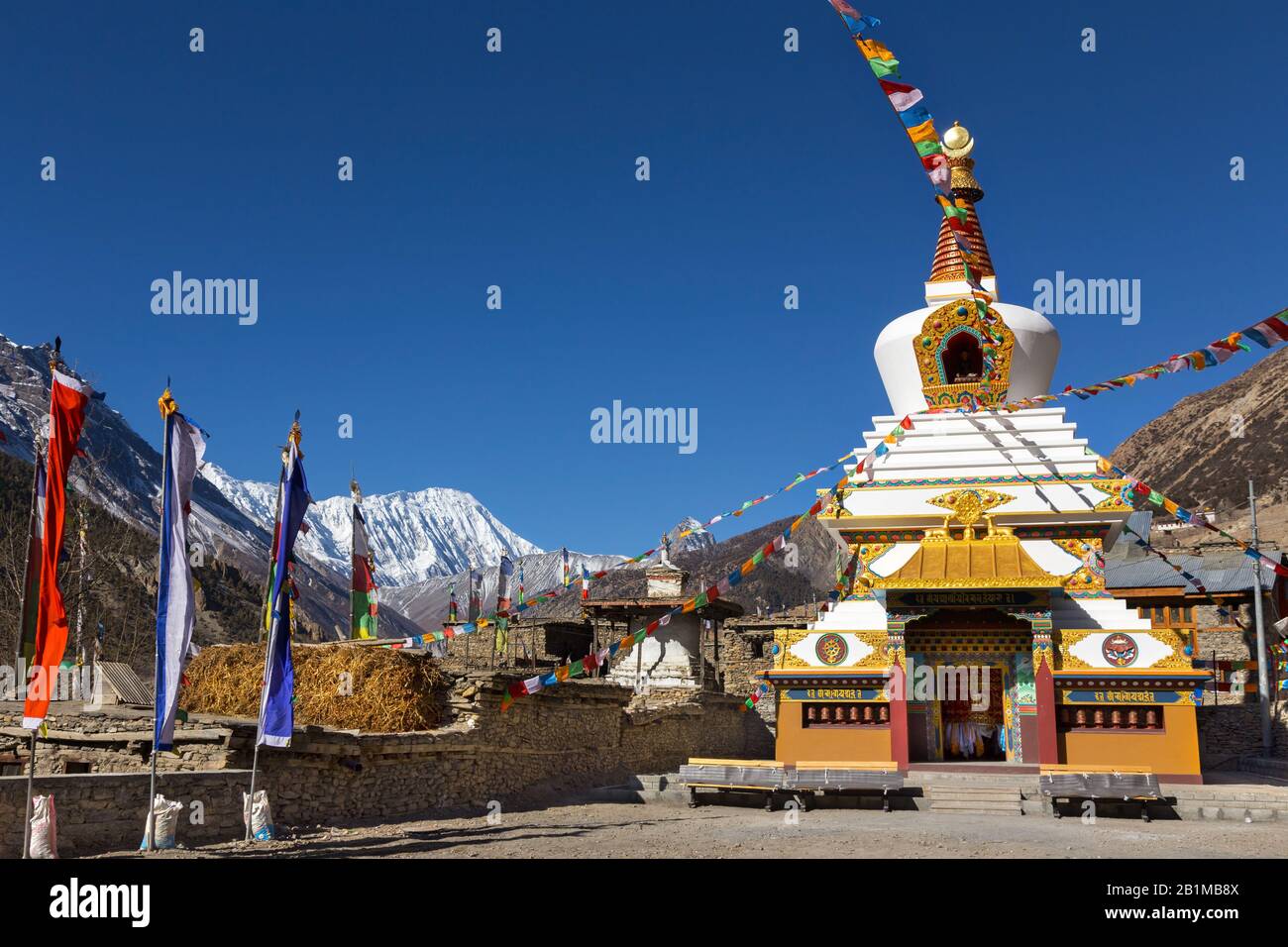 Massives riesiges buddhistisches Stupa-Denkmal und verschneite Himalaya-Bergspitzen im Manang Nepal Village auf Annapurna Circuit Wandertour Stockfoto