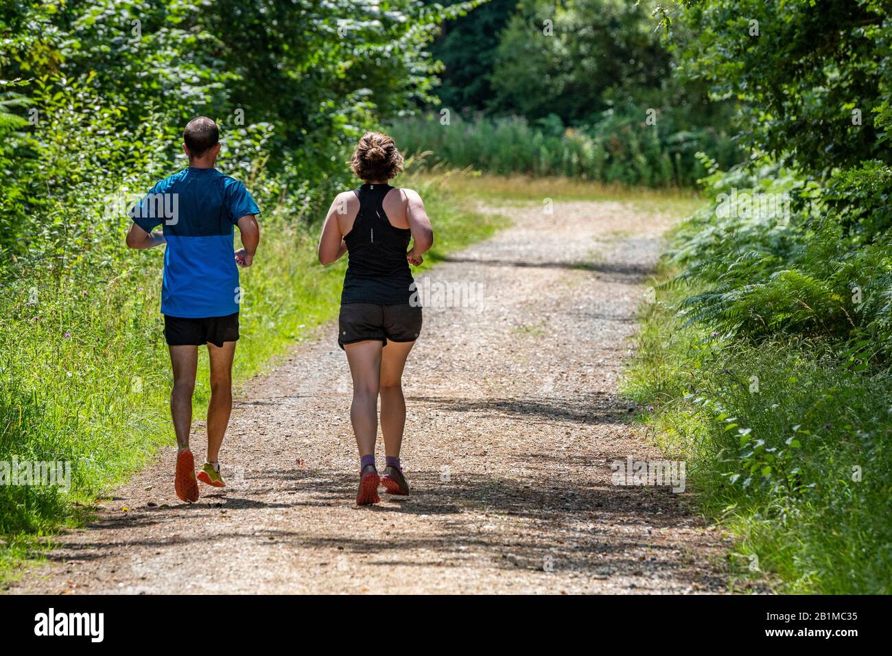 Ein Mann, eine Frau oder ein Mann und eine Frau, die laufen oder joggen, halten sich zusammen und teilen ihre Zeit miteinander. Stockfoto