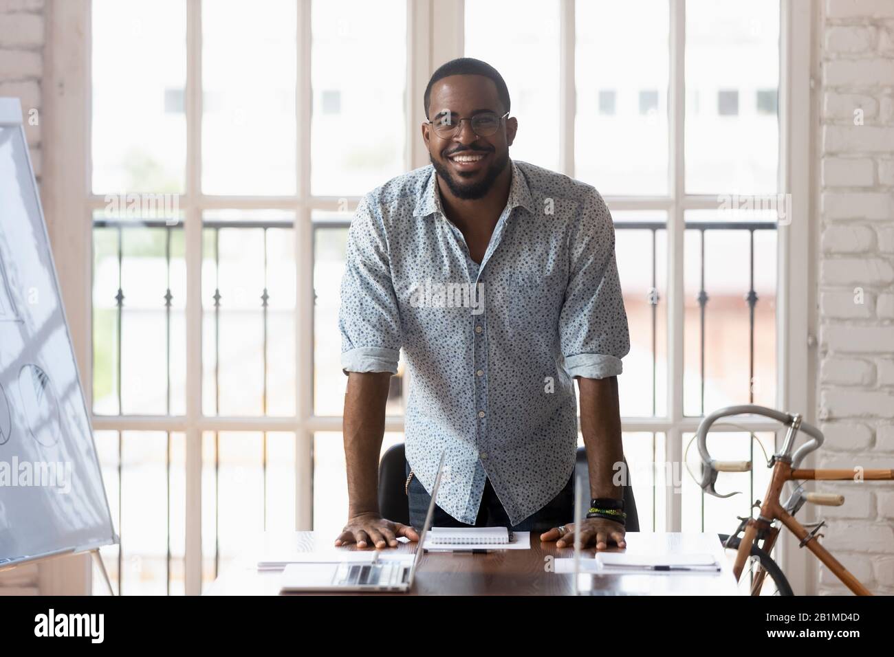 Afrikanischer Geschäftsmann posiert mit Blick auf die Kamera in der Nähe des Tisches im Sitzungssaal Stockfoto