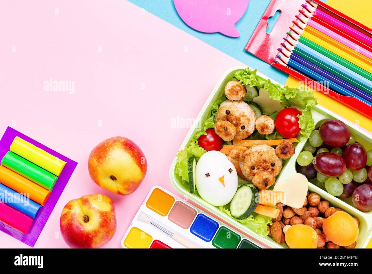 Schullunchbox mit gesundem Imbiss und lustigen Speisen - Häckchen, Gemüse, Obst, Nüsse. Zurück zum Schulhintergrund. Stockfoto