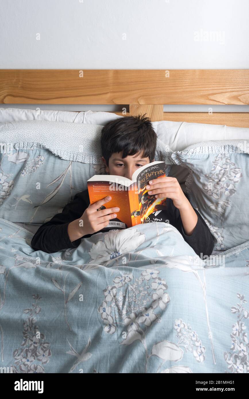 Young Boy liest Harry Potter Buch im Bett,.UK Stockfoto