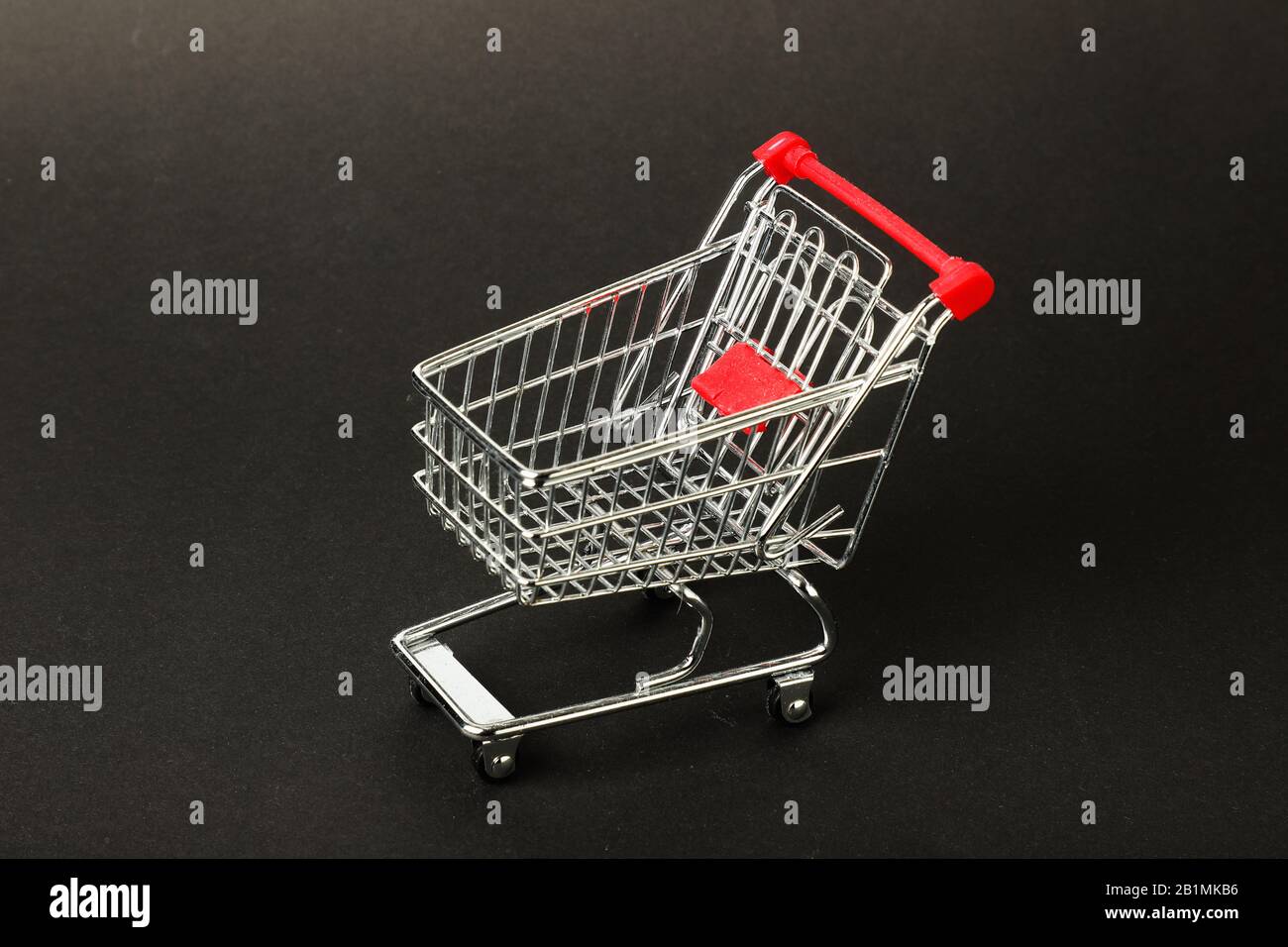Leerer Spielzeug-Einkaufswagen mit grauem Hintergrund. Stockfoto