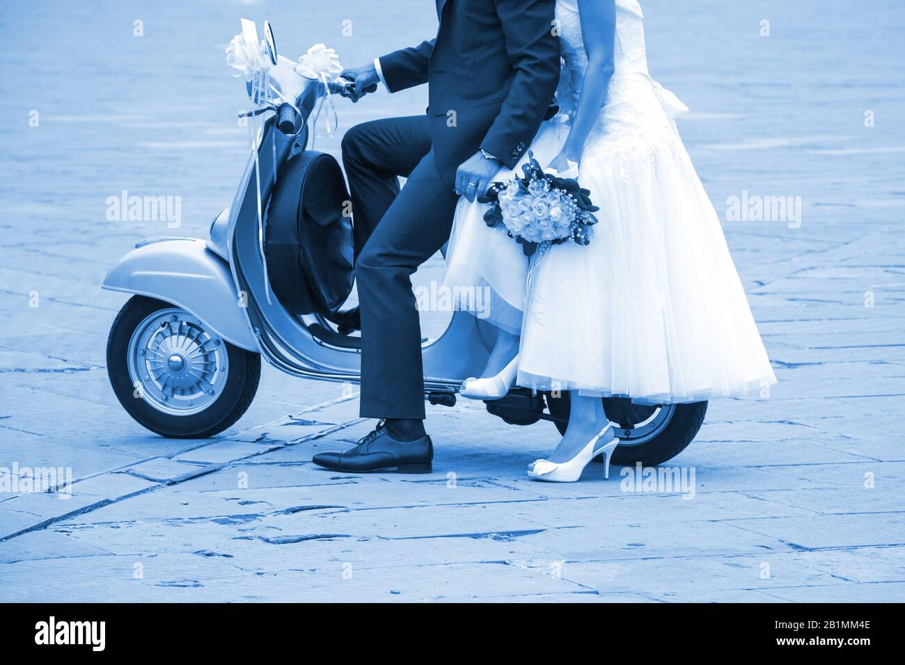 Junge Neuvermählte sind gerade verheiratet und posieren auf einem alten Roller. Classic Blue Pantone 2020 Jahresfarbe. Stockfoto