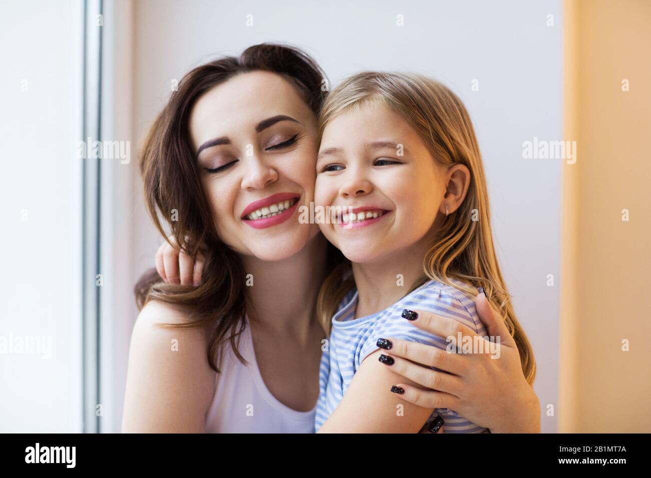 Junge Frau am Morgen umarmen sich mit einem kleinen Mädchen. Froher Muttertag Stockfoto