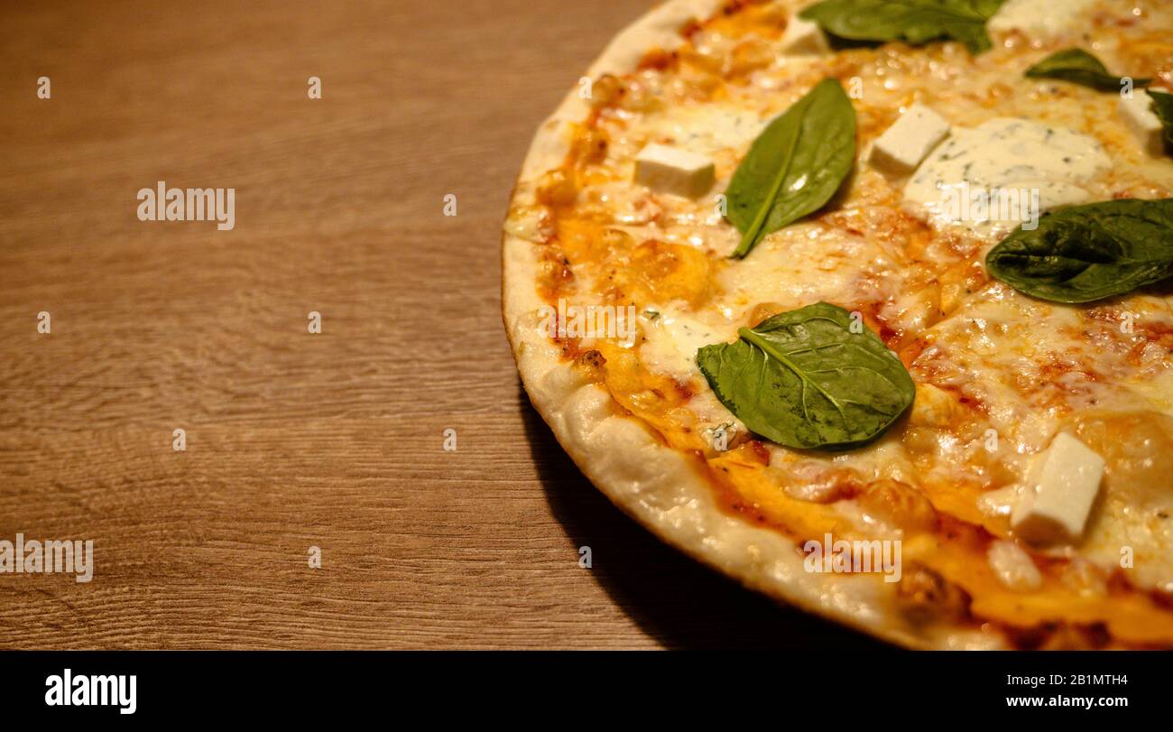 Drei Käse dünne Kruste frisch gebackene Pizza mit Basilikumblättern oben auf einem Holztisch Nahaufnahme mit Kopierraum Stockfoto