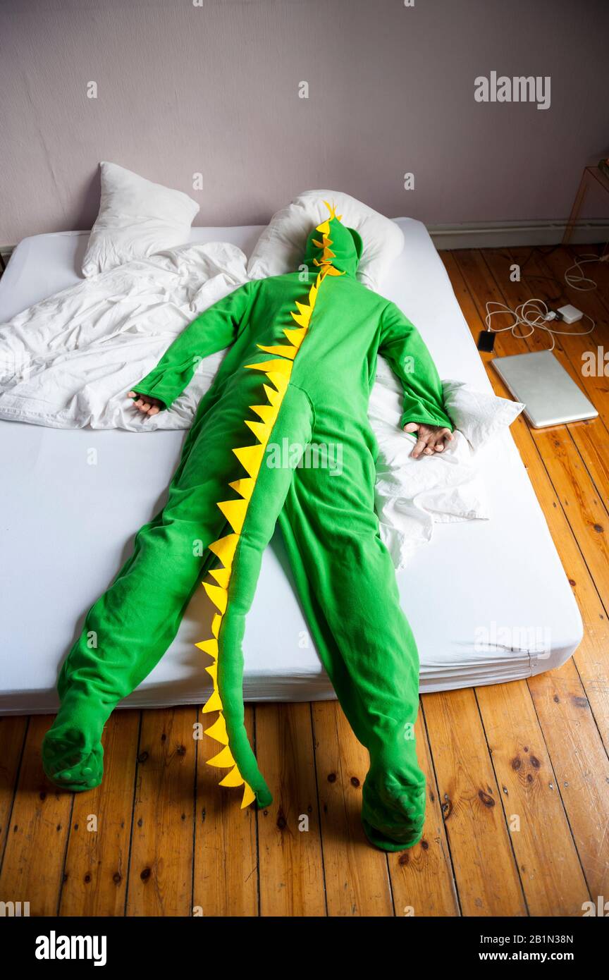 Lounge Eidechse Dinosaurier-Mann, der mit dem Gesicht nach unten auf einem Doppelbett auf dem Boden liegt Stockfoto