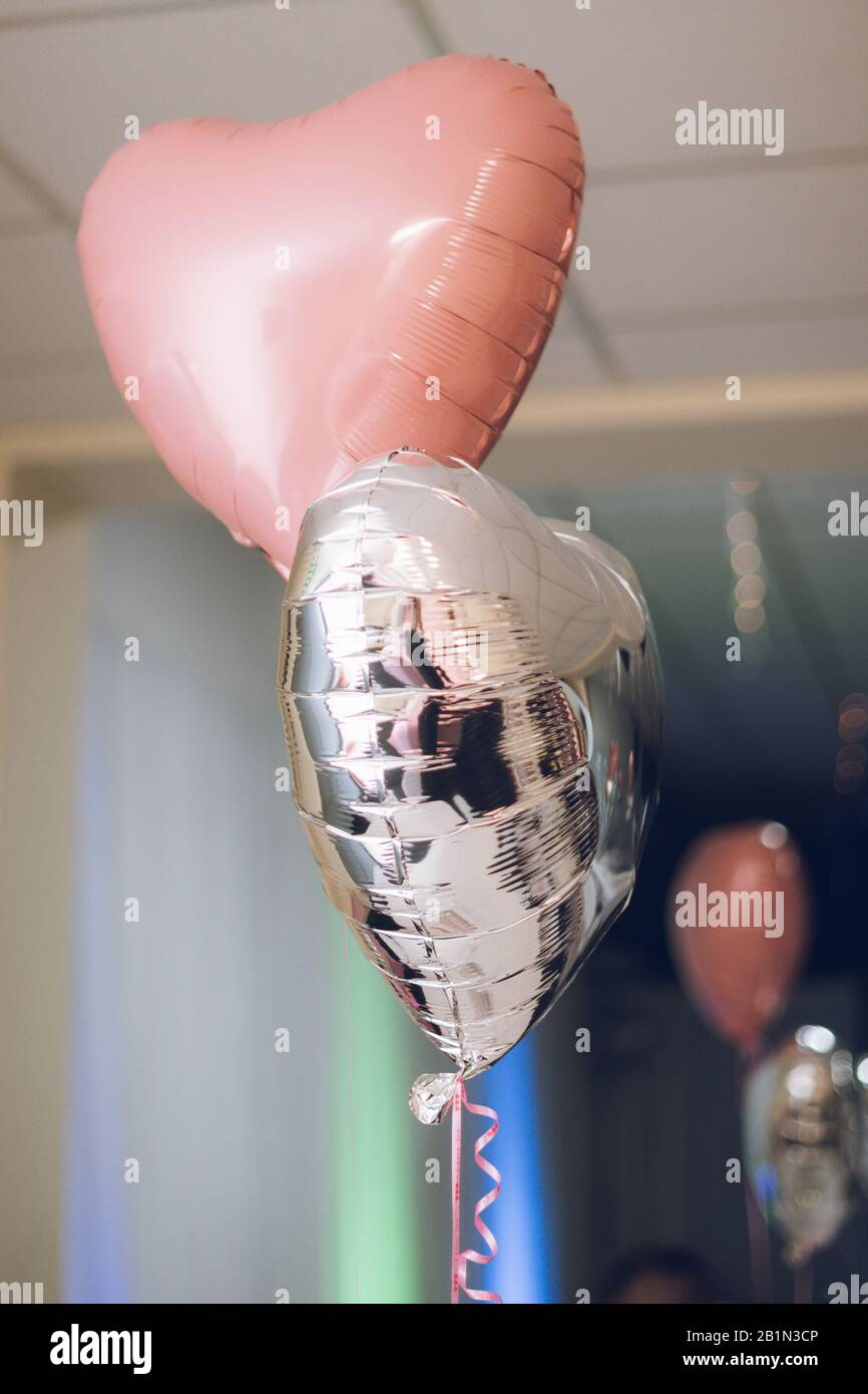 Herzförmige Ballons in Pink und Silber, mit denen ein Hochzeitslokal dekoriert wurde Stockfoto