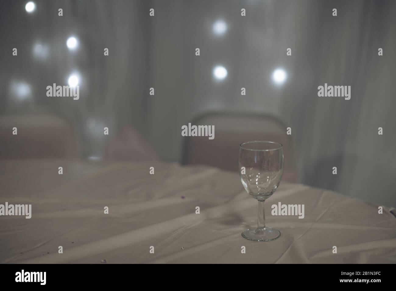 Ein leeres Glas auf einem Tisch, das bei einer Party oder einem Empfang mit einem weißen Tischtuch bedeckt ist Stockfoto