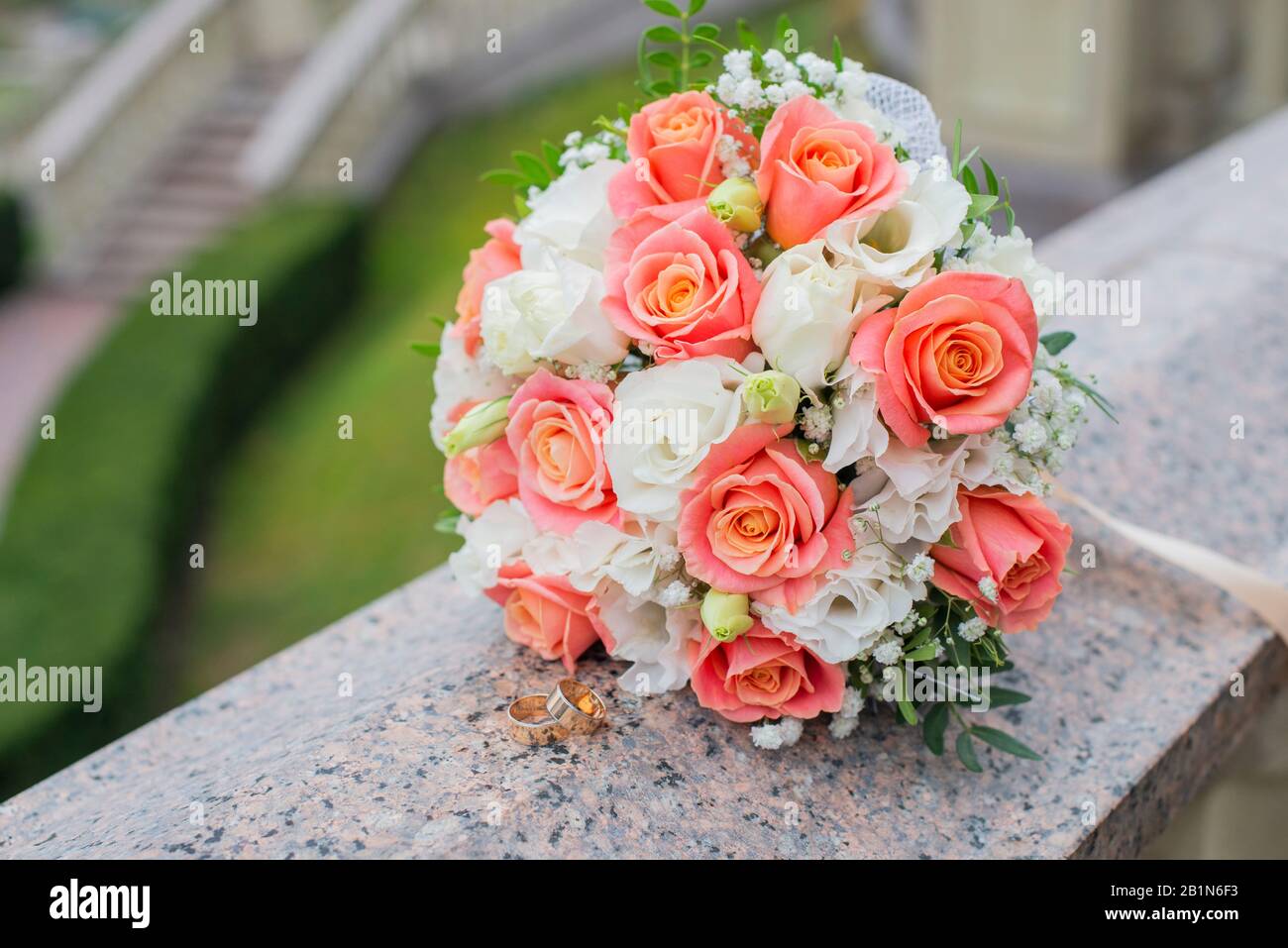 Hochzeitsgold läutet für die Zeremonie für die Neuvermählten mit einem Rosenstrauß in der Natur Stockfoto