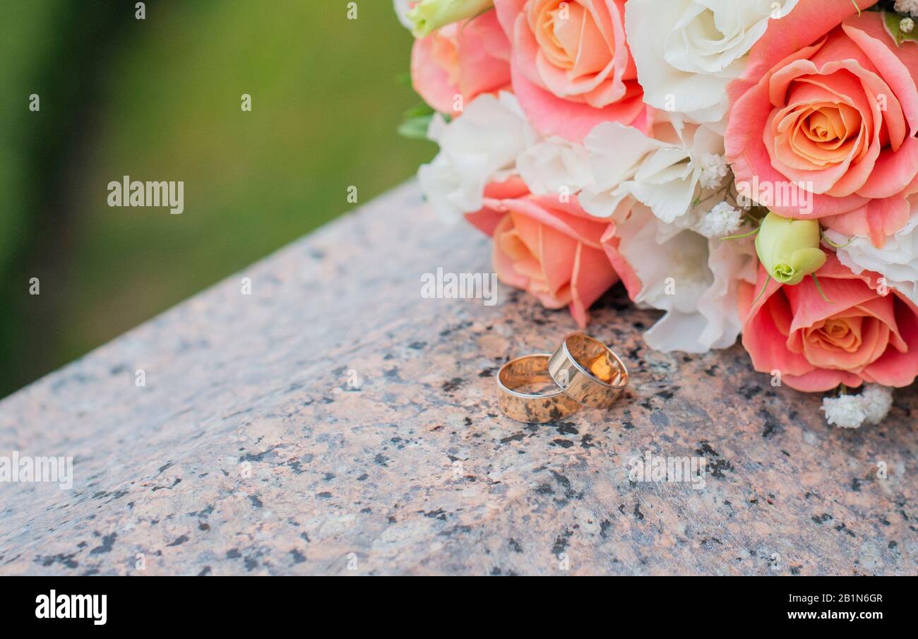 Hochzeitsgold läutet für die Zeremonie für die Neuvermählten mit einem Rosenstrauß in der Natur Stockfoto