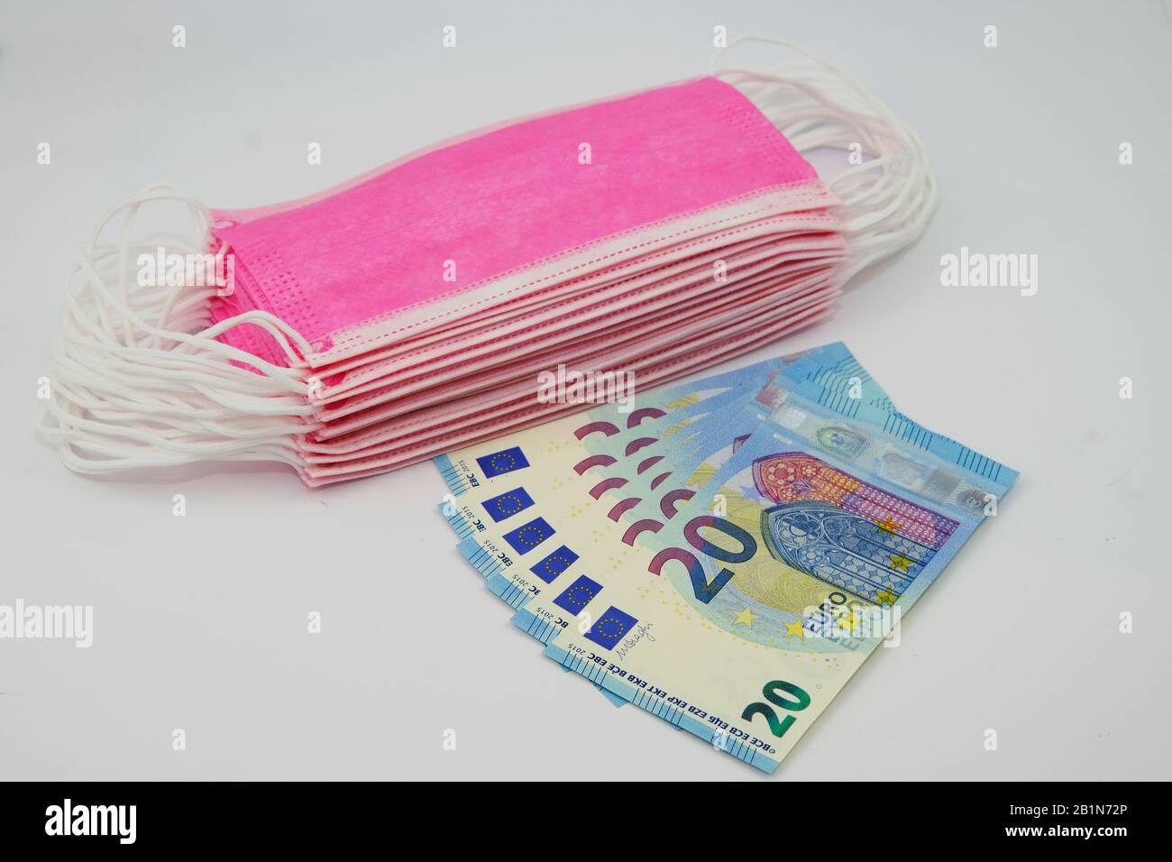 Rosafarbene Gesichtsmasken für den Virenschutz und 20 Euro-Banknoten. Konzept für den hohen Preis von chirurgischen Masken während der Epidemie in Europa Stockfoto