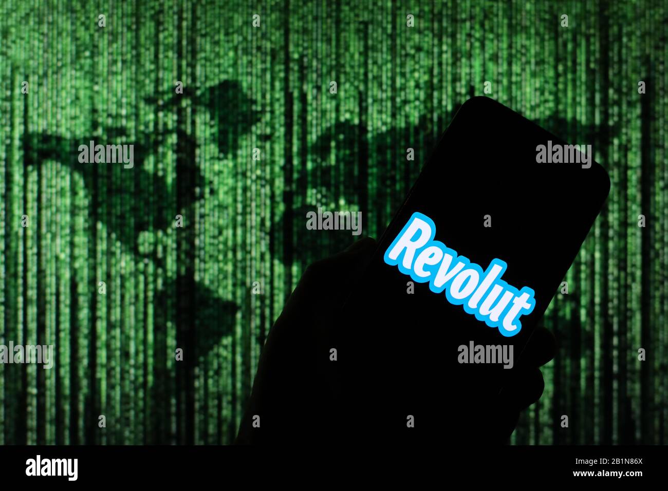 Revolut Online Money Exchange Firmenlogo auf dem Smartphone-Bildschirm mit Matrix-ähnlicher Weltkarte, die im Hintergrund verschwommen zu sehen ist Stockfoto
