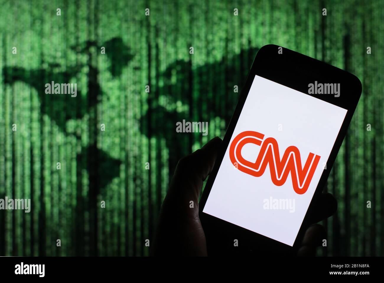 Das Firmenlogo der CNN-Mediennachrichten wird auf dem Smartphone-Bildschirm mit einer Matrix-ähnlichen Weltkarte angezeigt, die im Hintergrund verschwommen zu sehen ist Stockfoto