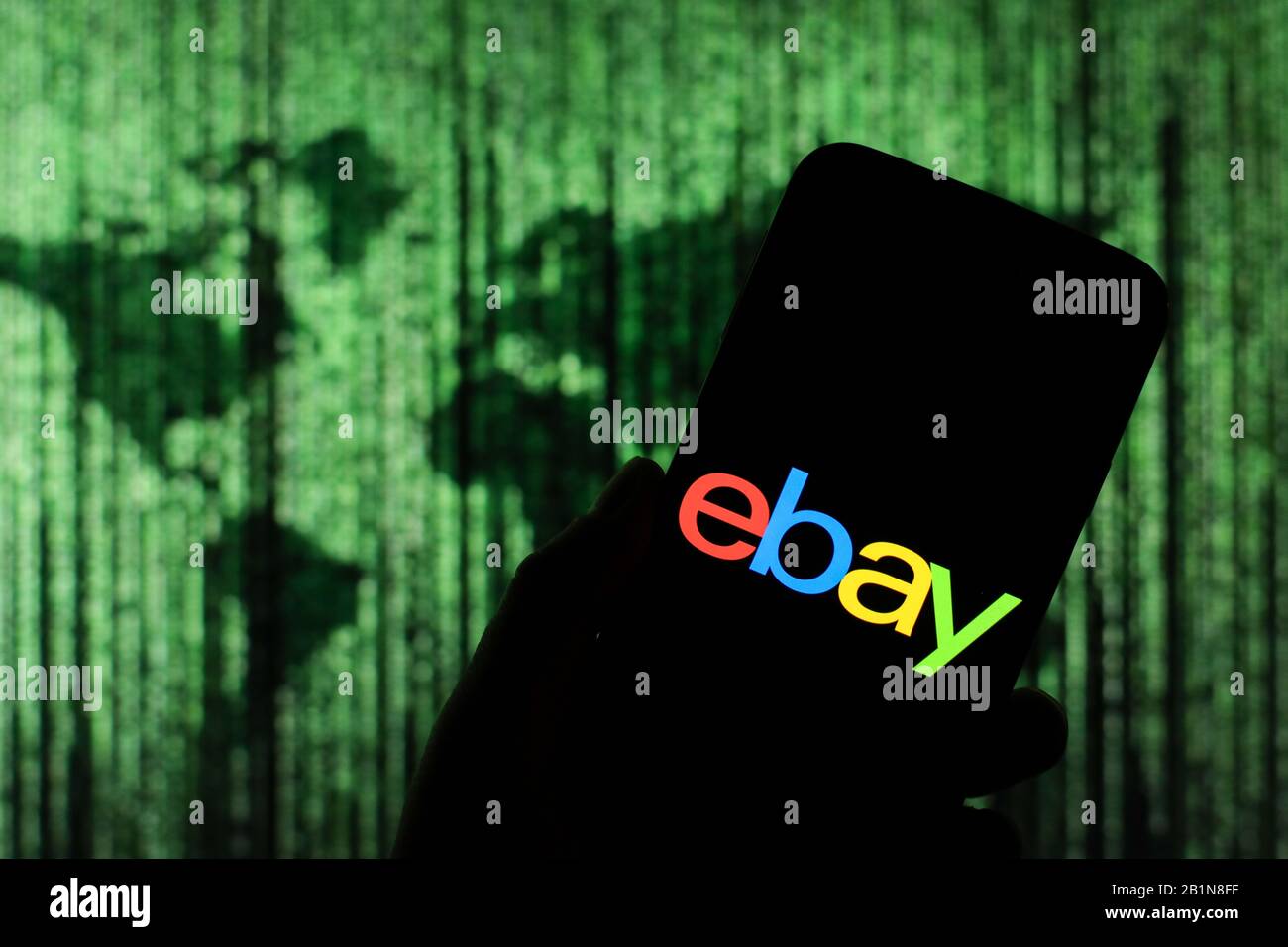 Das Logo des Unternehmens eBay wird auf dem Smartphone-Bildschirm mit einer Matrix-ähnlichen Weltkarte angezeigt, die im Hintergrund verschwommen zu sehen ist Stockfoto