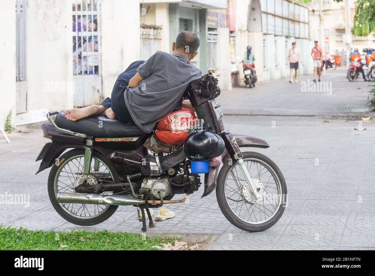 Saigon (Ho-Chi-Minh-Stadt) - EIN Mann, der sich auf seinem Motorrad auf der Straße von Saigon, Vietnam, Südost-Asien entspannt. Stockfoto