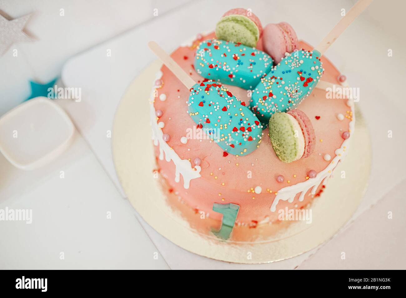 Rosa schöner großer Kuchen mit grüner Nummer eins, dekoriert mit Lebkuchen und Makronen, Draufsicht Stockfoto