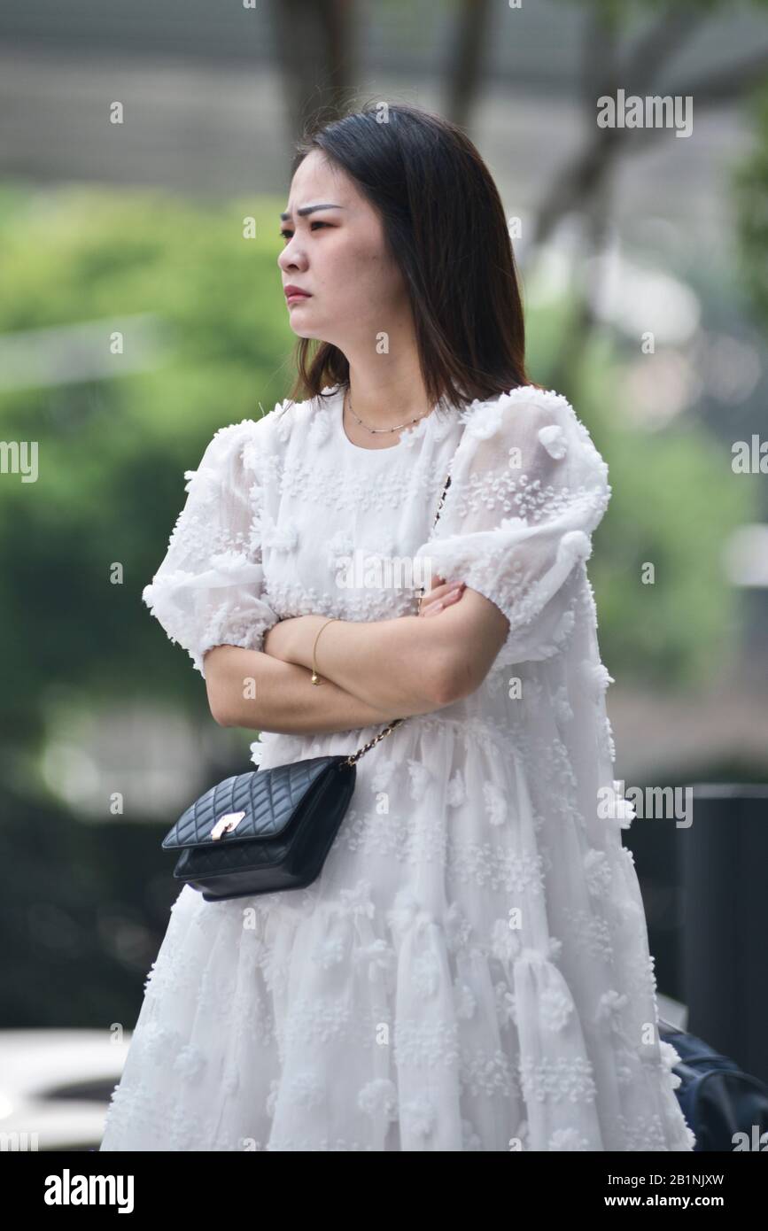 Wuhan: Eine junge Frau mit einem weißen Kleid und einer schwarzen Geldbörse, die an der Ausfahrt der U-Bahn-Station Chuhe Hanije, Zhong bei Lu Street, wartet. China Stockfoto