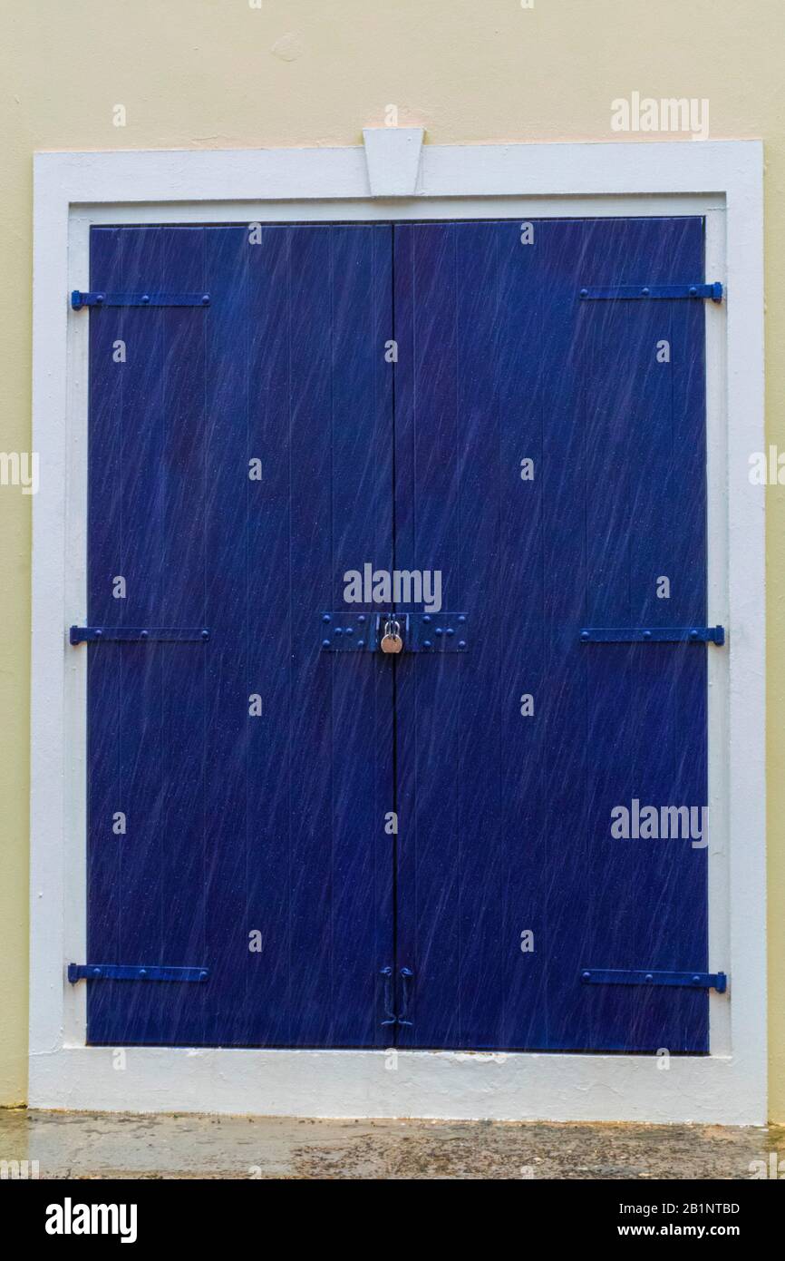 Karibische Ladentür, Unter Schloss und Schlüssel, blaue Tür mit weißer Verkleidung, unberührte Architektur der Inseln, verschlossene Holztür, ein mit einem Vorhängeschloss versehenen Gebäude Stockfoto
