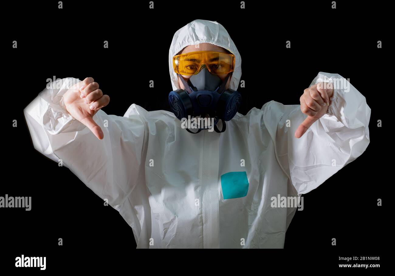 Frau Daumen unten Schild in einer chemischen Schutzkleidung und Gasmaske mit gelber Brille am schwarzen Hintergrund, Wissenschaftlerin im Sicherheitsanzug, Safe Stockfoto
