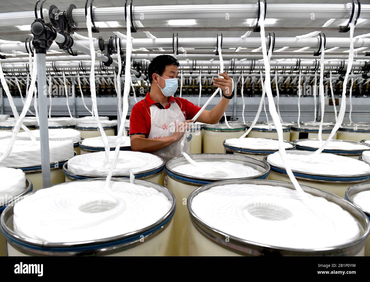 Ein chinesischer Arbeiter überwacht die Produktion von Garn in einer Textilfabrik im Xiayi County, Shangqiu City, der zentralchinesischen Provinz Henan am 26. Februar 202 Stockfoto