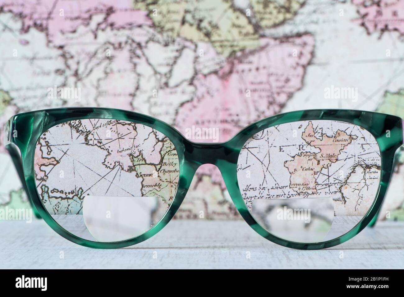 Brillengläser mit Bifocals und schwarzem blauem Rahmen verschmiert Mode Vintage Style auf Wood Desk mit Weltkarten-Hintergrund. Stockfoto