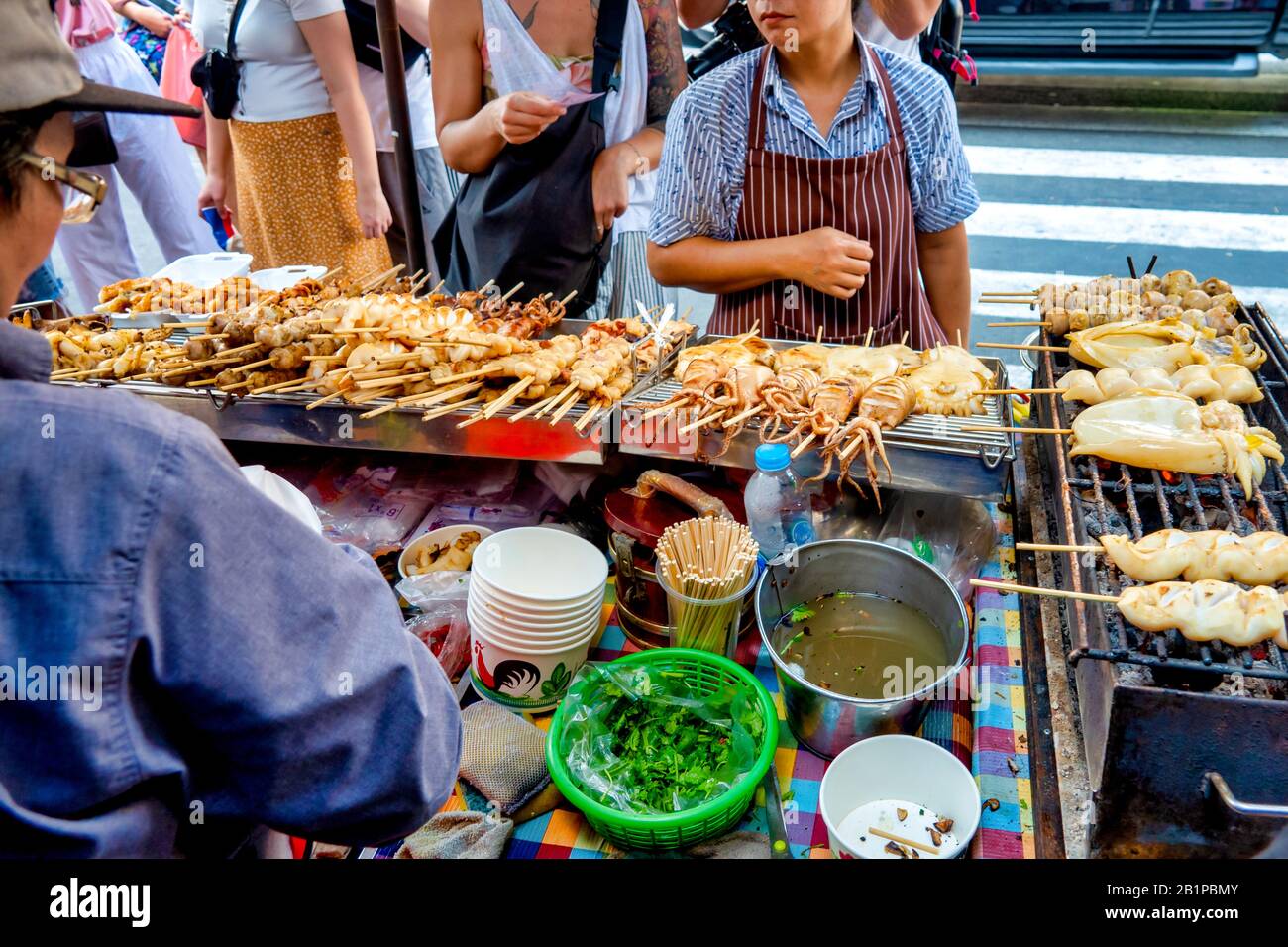 Frau, die Plaa Mhuk Yang (gegrillter Tintenfisch) auf Thanon Yaowarat, Bangkok verkauft Stockfoto