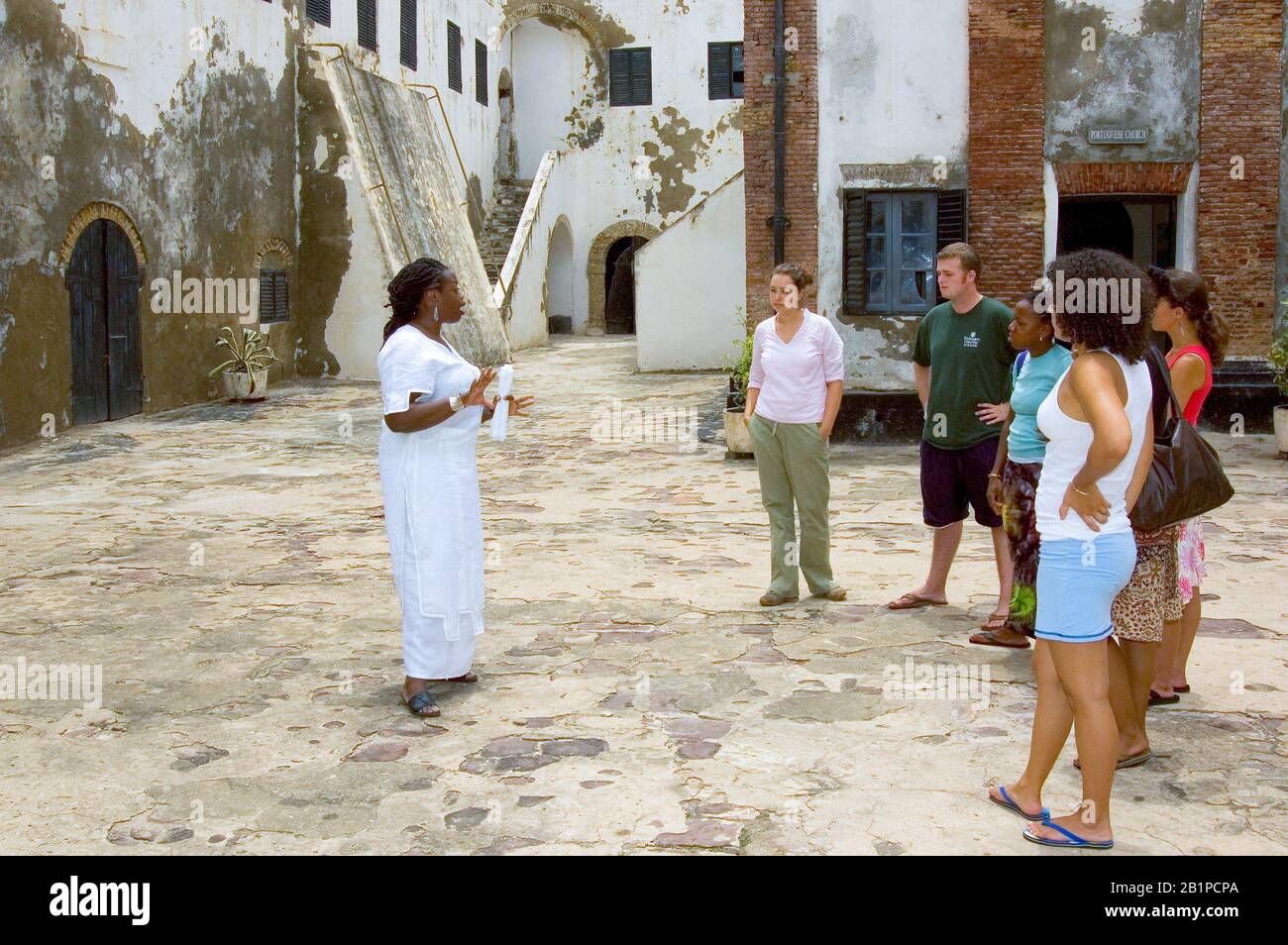 Universitätsprofessor und Studenten, die das Schloss Elmina besuchen und die das ehemalige Slave-Viertel Ghanas betrachten Stockfoto