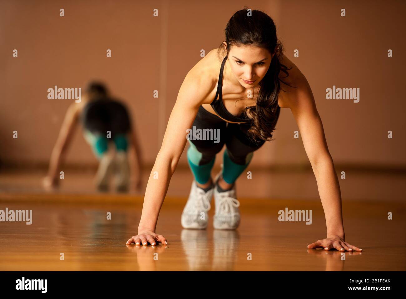 Schöne passende Frau arbeitet in einem Fitnessstudio, Push-ups für Körper Kraft Stockfoto