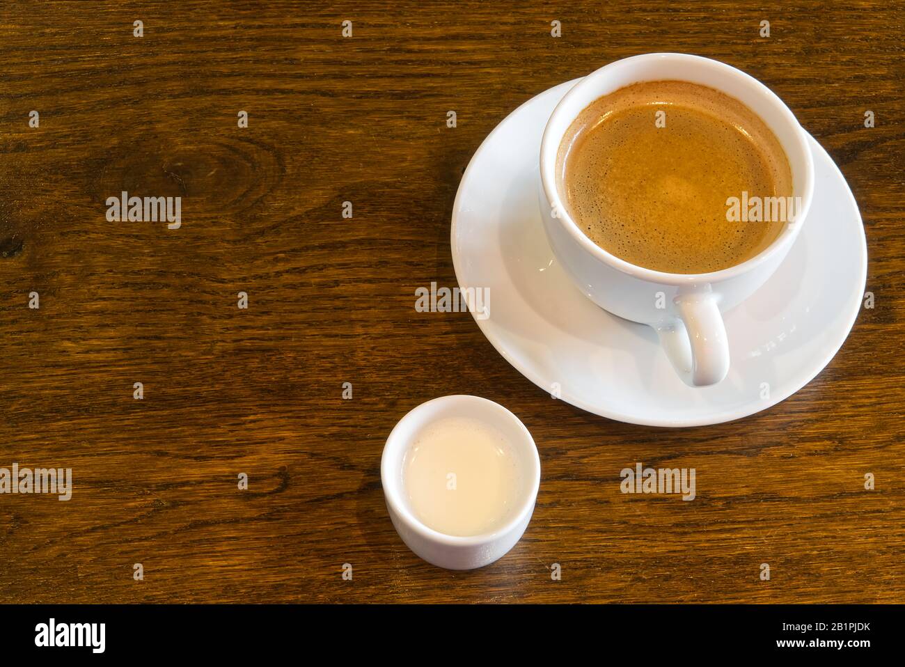 Tasse Kaffee auf Holztisch im Restaurant- oder Kaffeehaus. Weiße Keramikbecher mit Blick oben und Kopierbereich Stockfoto
