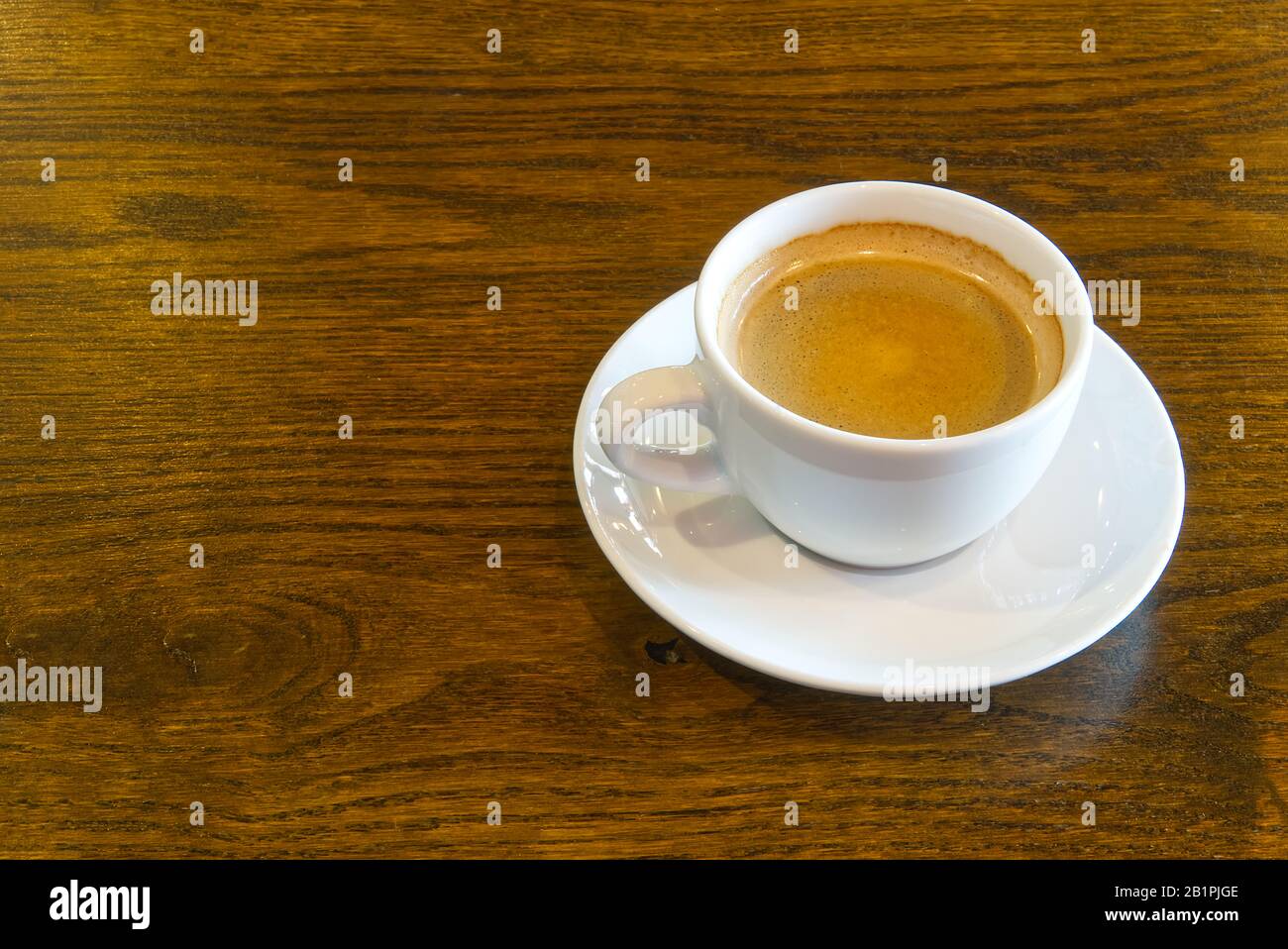 Tasse Kaffee auf Holztisch im Restaurant- oder Kaffeehaus. Weiße Keramikbecher mit Blick oben und Kopierbereich Stockfoto