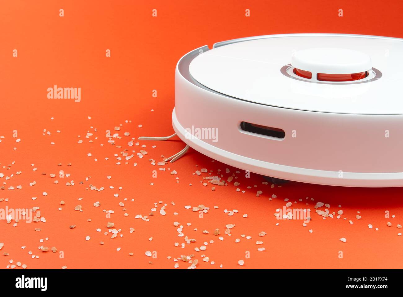 Der Roboter-Staubsauger im Job entfernt Rückstände von sich aus. Roboter-Staubsauger isoliert auf rotem Hintergrund. Nahaufnahme Foto Stockfoto