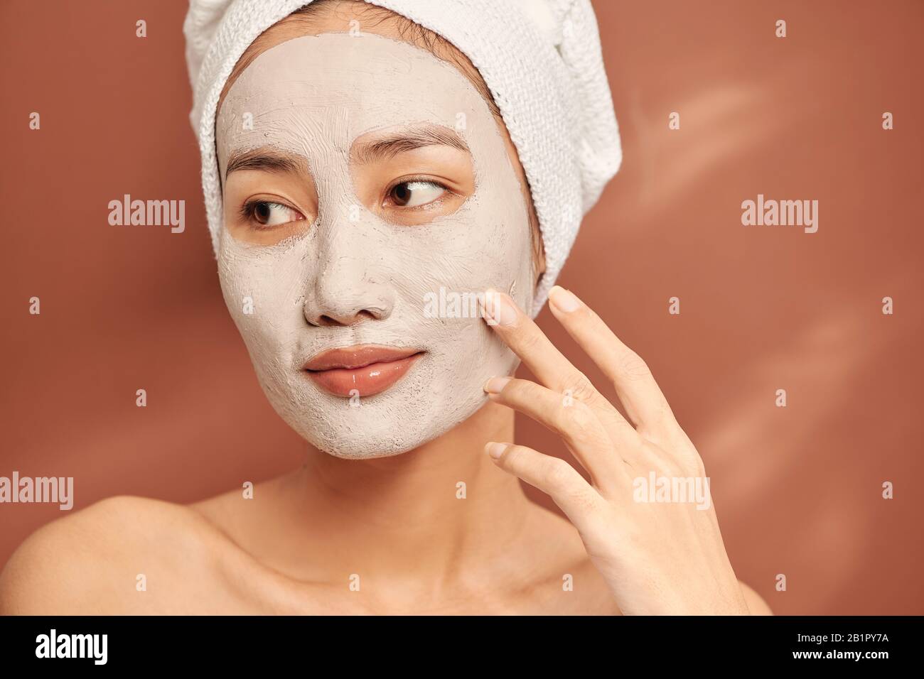 Attraktive Frau Anwendung Clay Mask auf ihrem Gesicht. Stockfoto