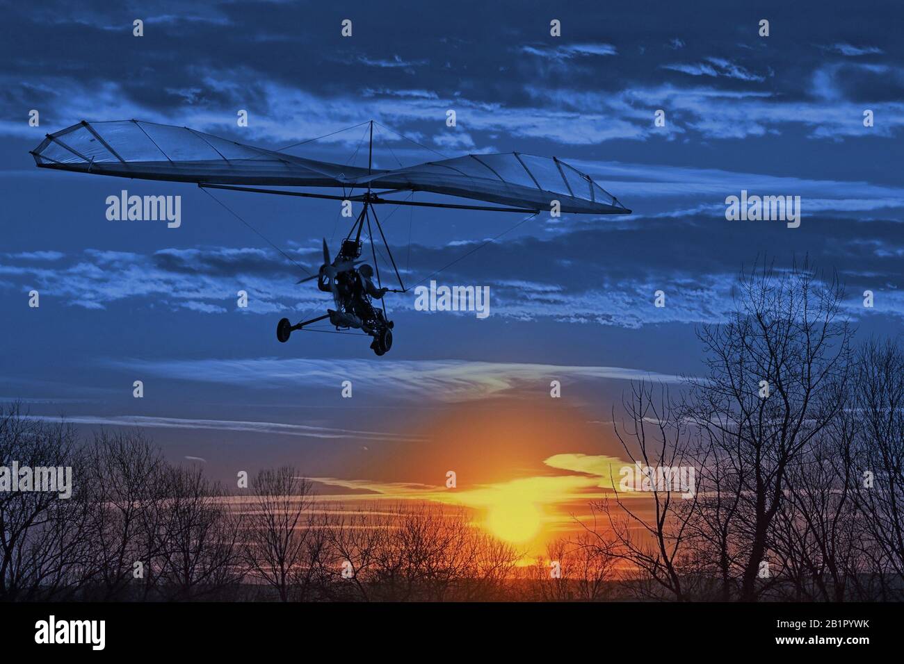 Der motorisierte Drachenflieger fliegt im Sonnenuntergang. Classic Blue Pantone 2020 Jahresfarbe. Stockfoto