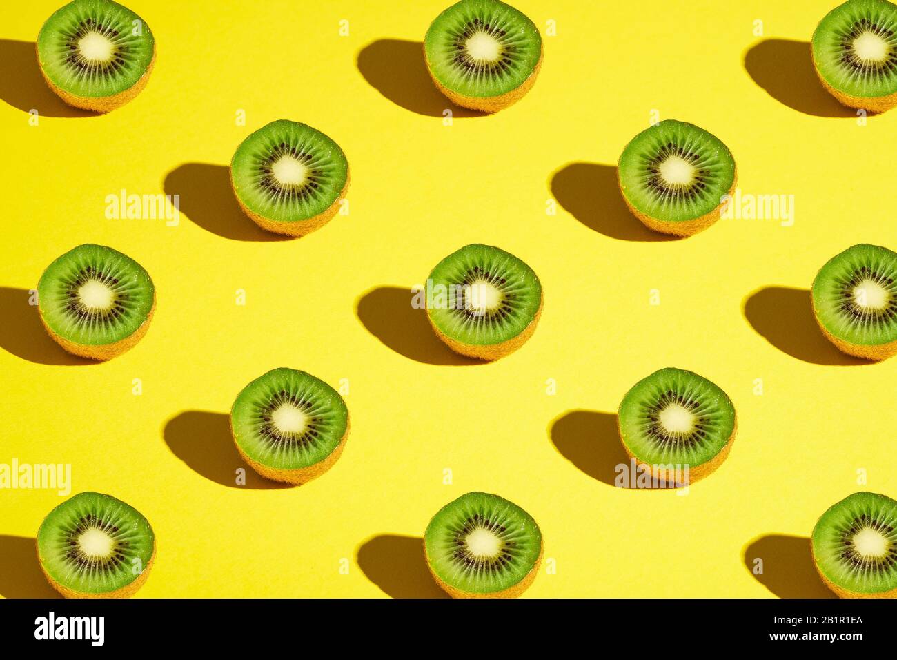 Kiwi Fruits Elemente Muster Layout, minimalistisches abstraktes Design flaches Lay, gesundes Essen, Winkelansicht, leuchtend gelber Hintergrund Stockfoto