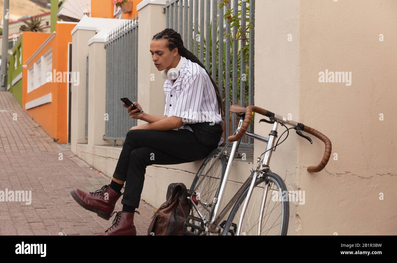 Gemischter Rennmann mit Dreadlocks über sein Telefon Stockfoto