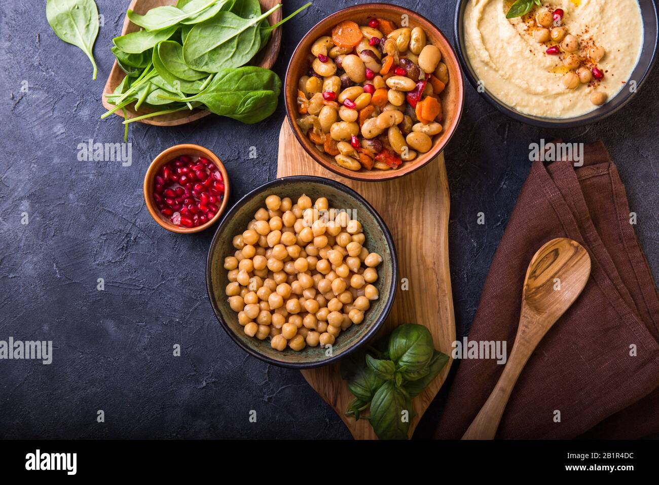 Gekochte Nierenbohnen, weiße Bohnen, Kichererbsen und hausgemachter Hummus auf einem Teller, Steinhintergrund Stockfoto