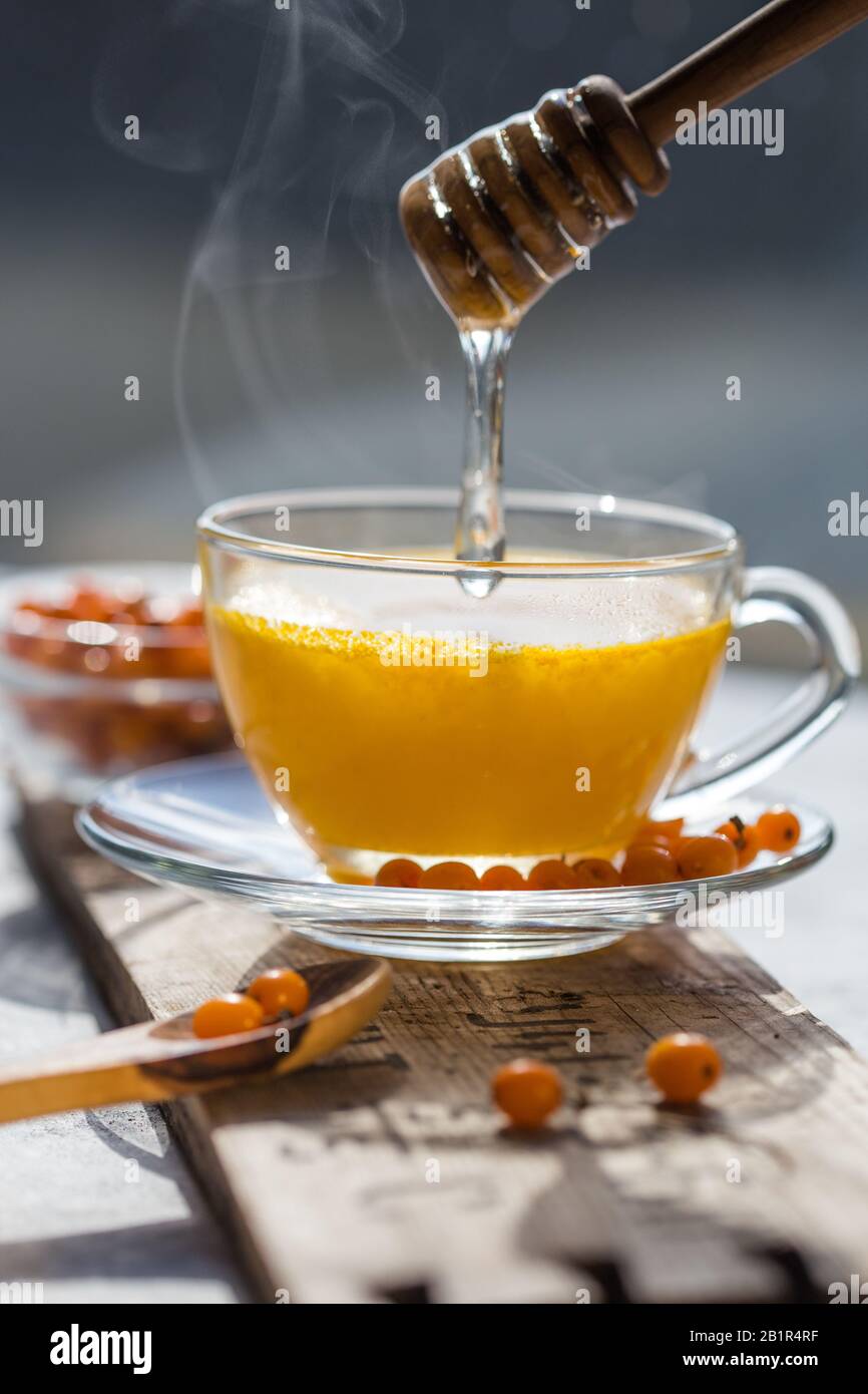 Heißer Sanddorntee. Vitaminisch gesunder Meeresbuckdorntee mit Honig auf Holzgrund Stockfoto