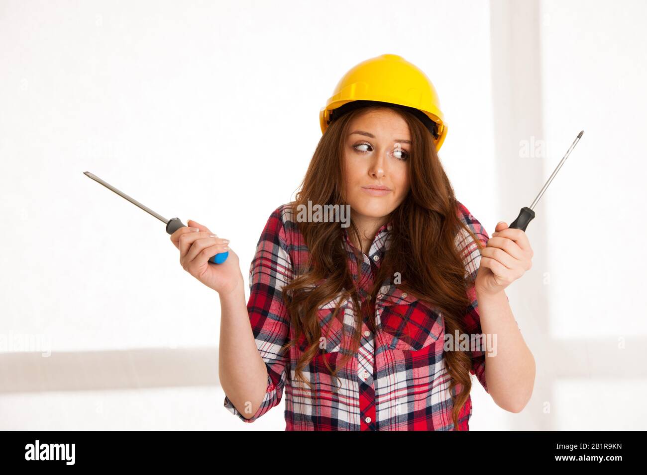 Unsichere Frau mit zwei Schraubendrehern Stockfoto