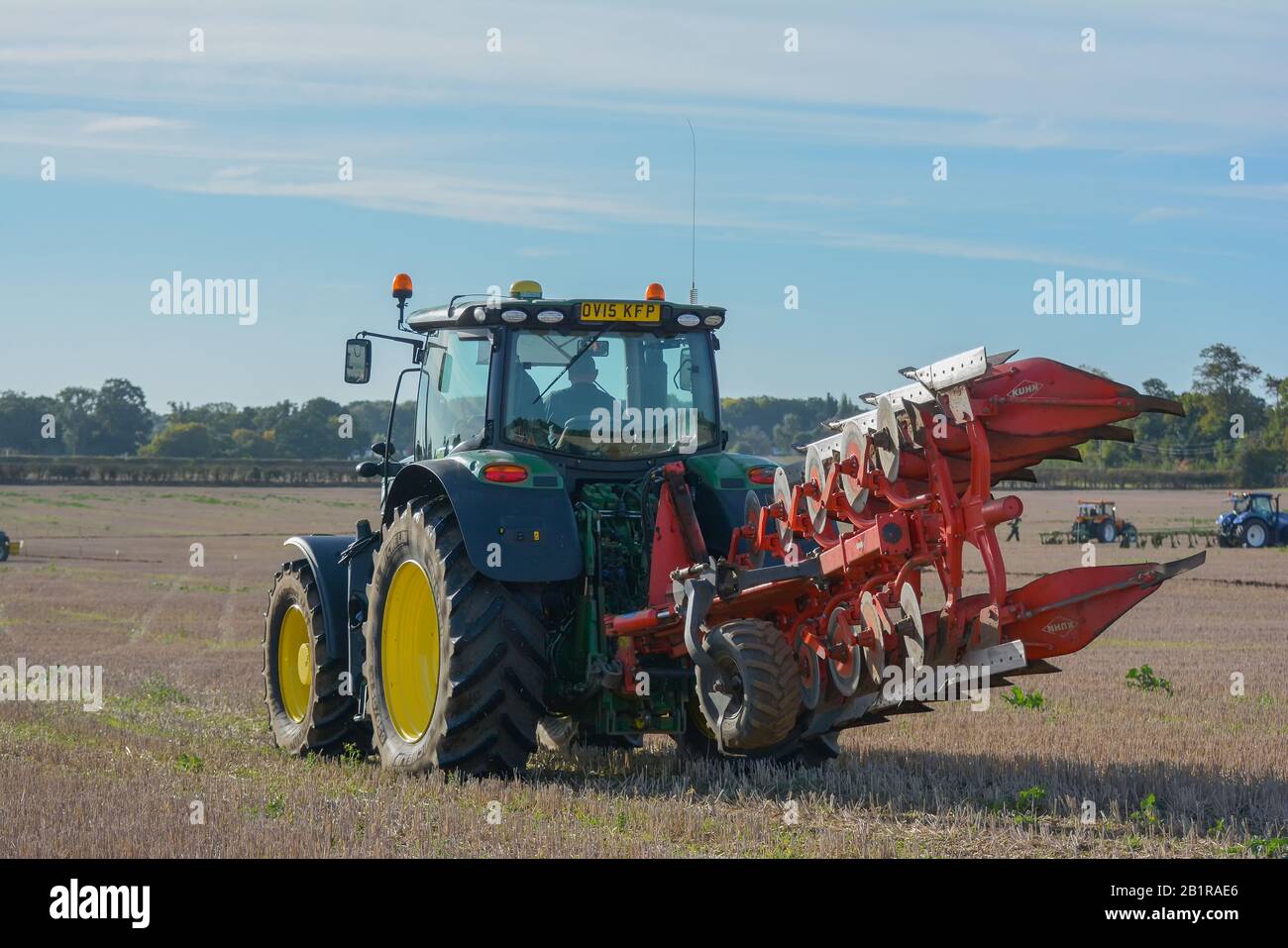 Roter moderner Traktor mit gelben Rädern Pflügen Feldpflug England Landwirtschaft Massey Ferguson Match Wettbewerb Land County Stockfoto