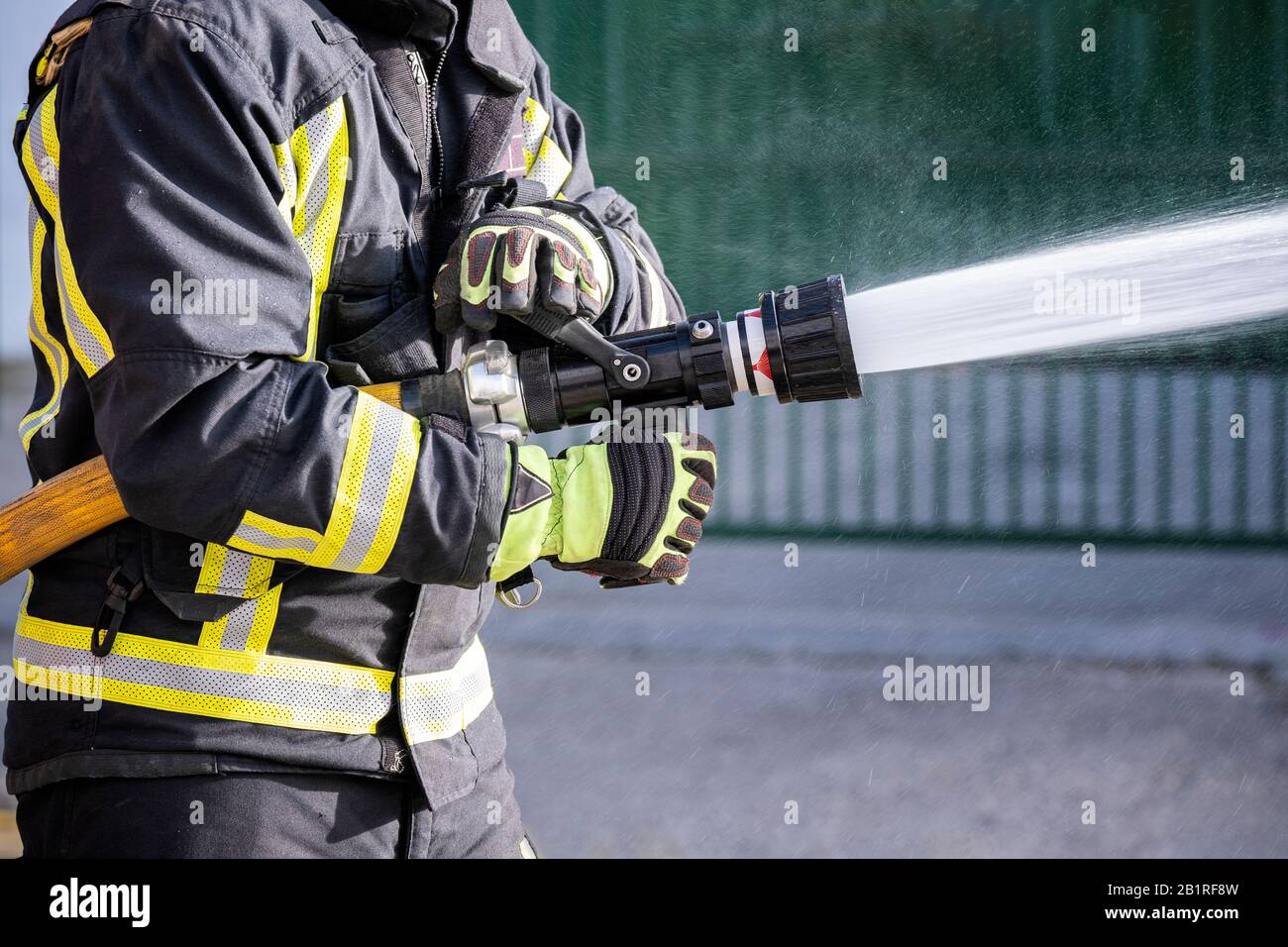 Feuerwehrleute, die Feuerlöscher und Löschwasser zur Brandbekämpfung einsetzen Stockfoto