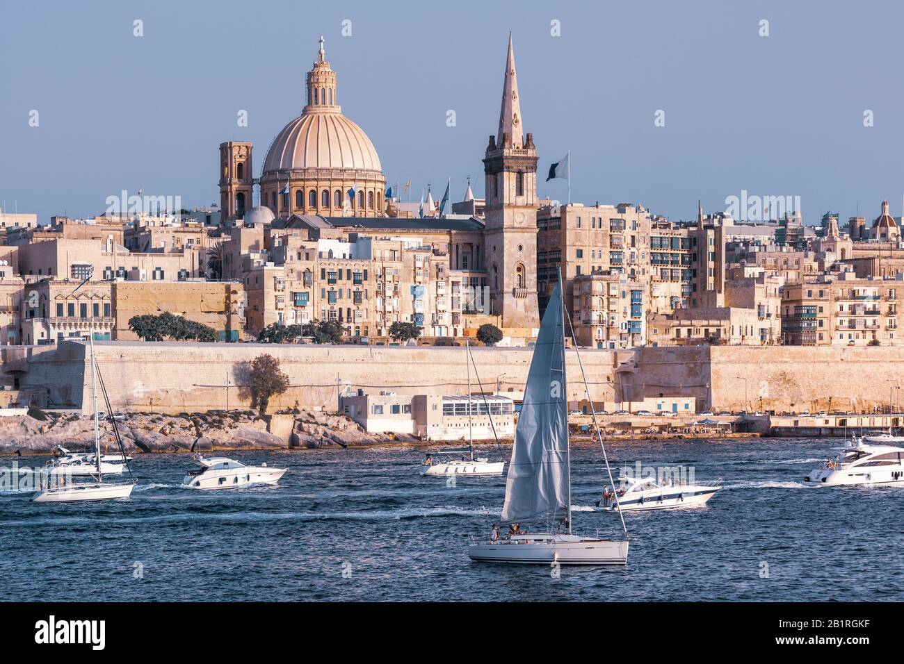 Weiße Yacht und Boote im Hafen von Valletta, Unserer Lieben Frau von der Kirche Mount Carmel und der anglikanischen Pro-Kathedrale St. Paul im Hintergrund, Valletta, Malta Stockfoto