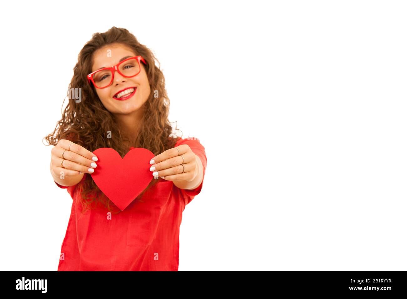 Schöne junge Frau in Rot, die ein Herz für Valentinstag hält, isoliert über weißem Hintergrund Stockfoto