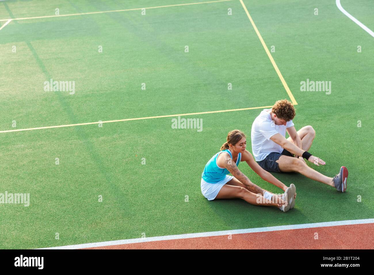 Attraktives, gesundes Fitness-Paar, das Dehnübungen im Stadion macht Stockfoto