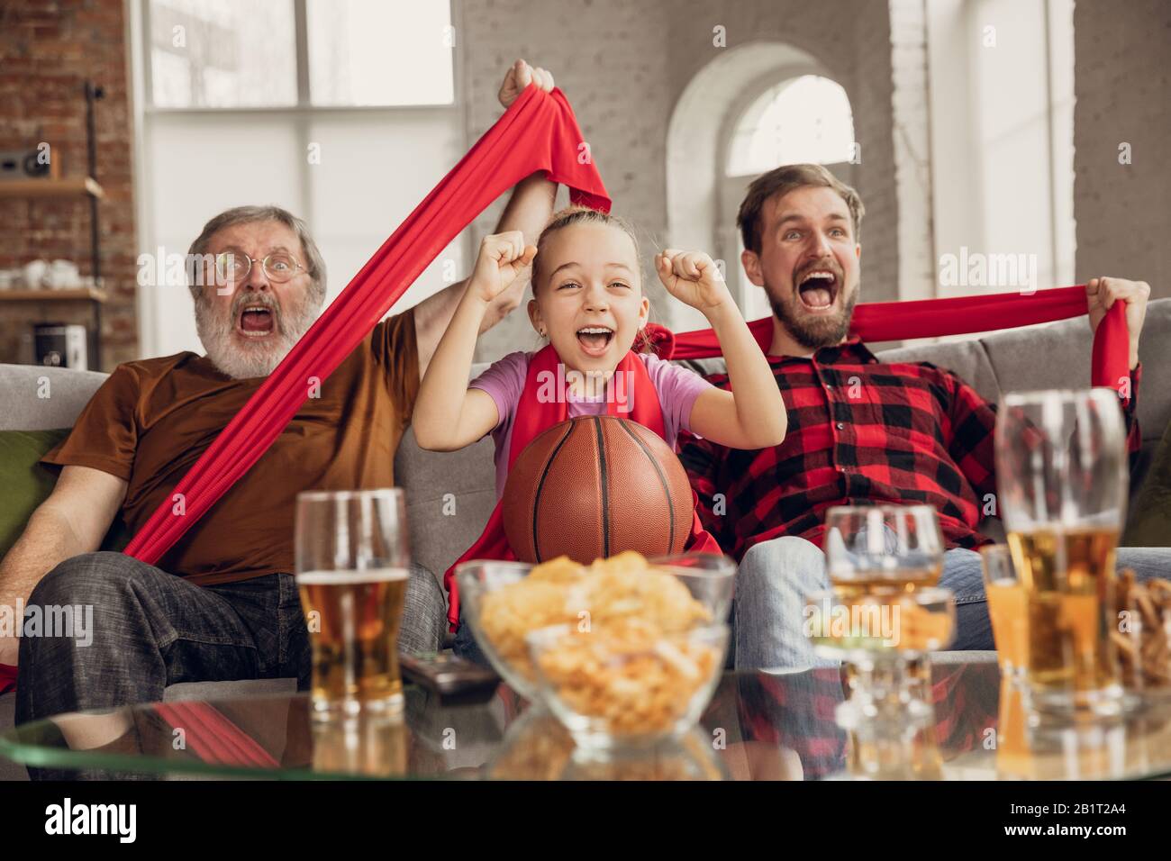 Sieg. Aufgeregt, glückliche Familie beim Basketballspiel, Meisterschaft auf der Couch zu Hause. Fans emotional jubeln für Lieblings-Nationalmannschaft. Tochter, Vater und Opa. Sport, Fernsehen, Spaß haben. Stockfoto