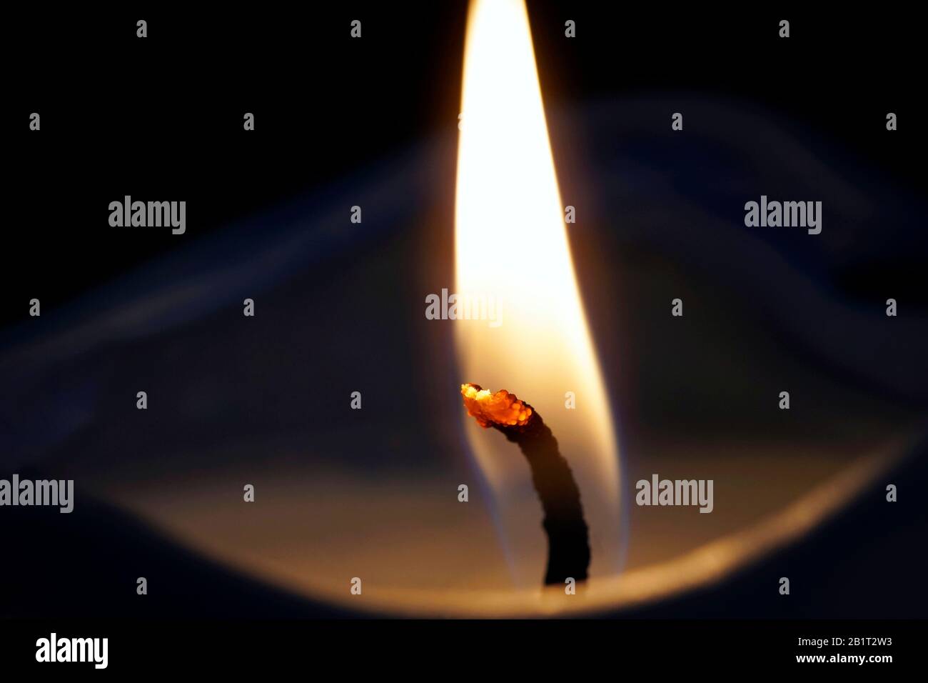 Die Nahaufnahmen einer brennenden Kerze, die auf dem schwarzen Hintergrund isoliert ist Stockfoto