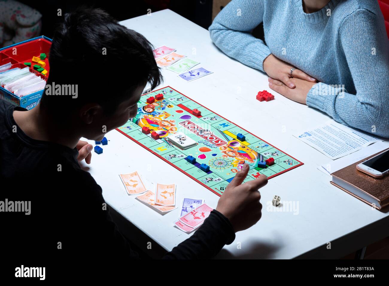 Der Junge würfelt die Würfel auf dem Monopolbordspiel Stockfoto
