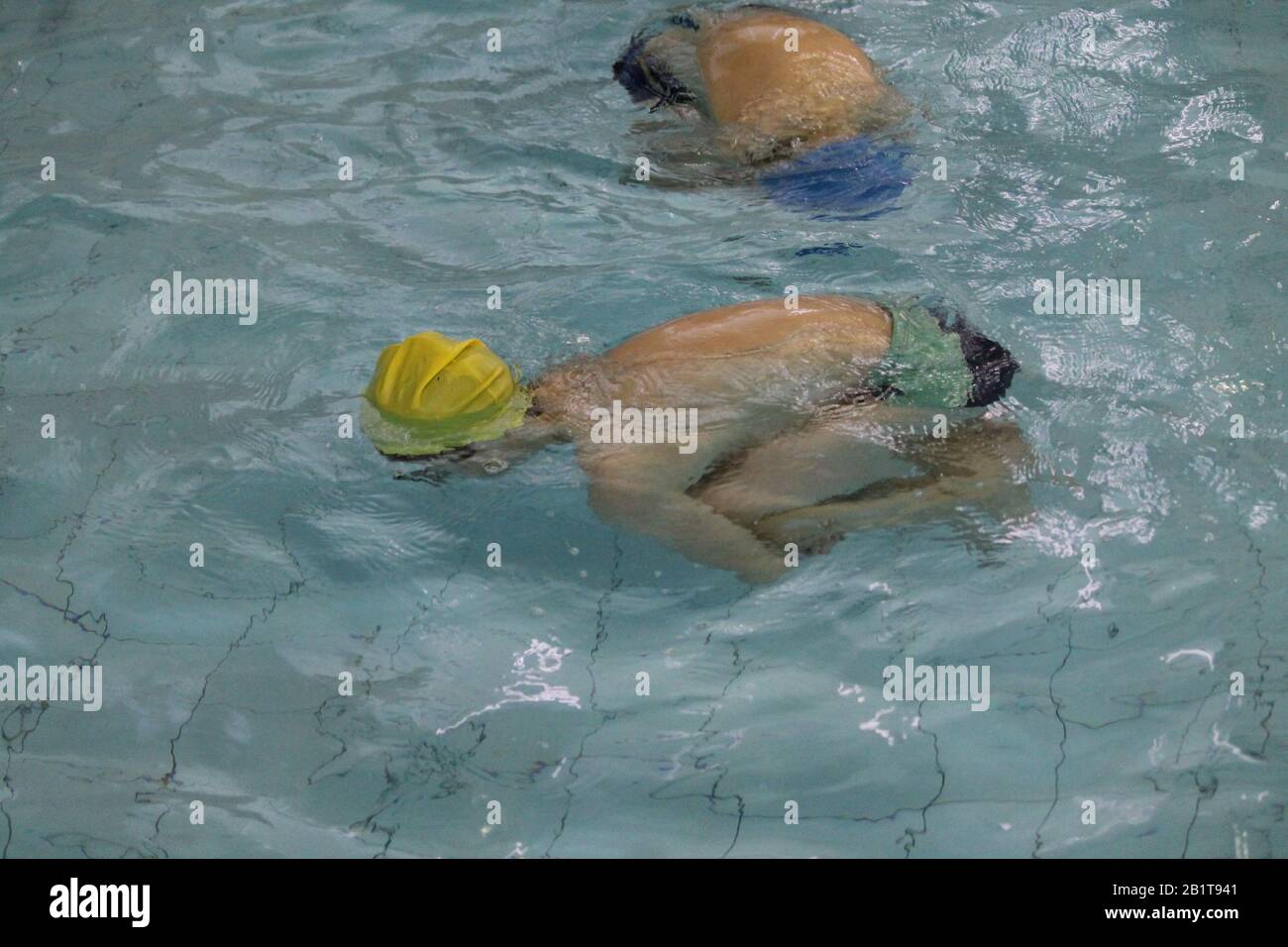 Kleine Schuljungen in kristallblauem Wasser im Schwimmbad auf der Lektion körperliches Training Stockfoto